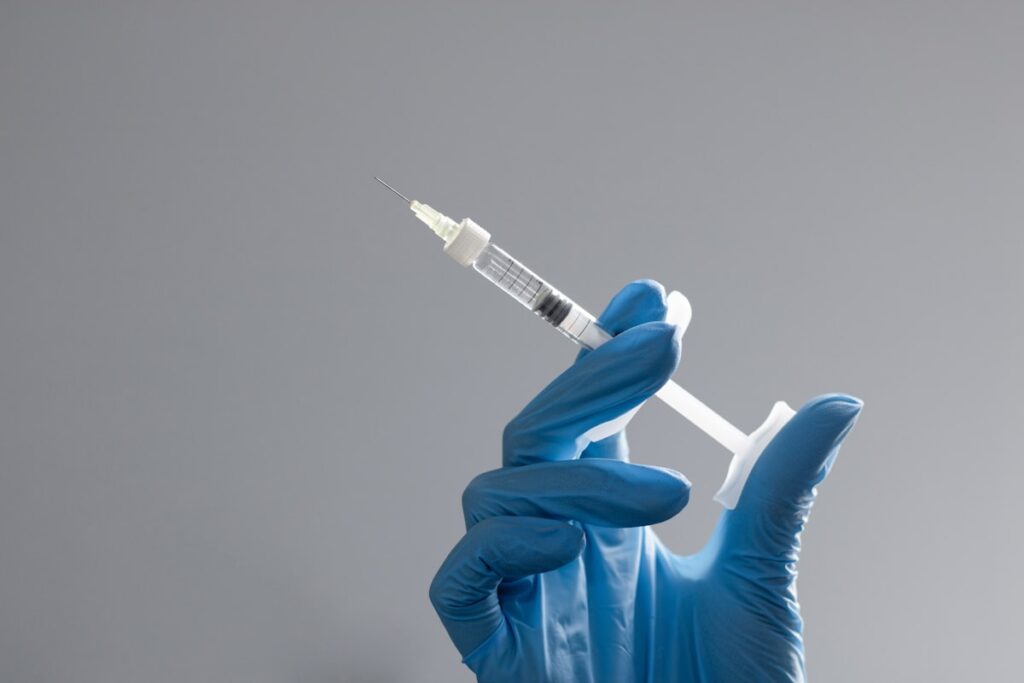 Gloved hand handling a research syringe
